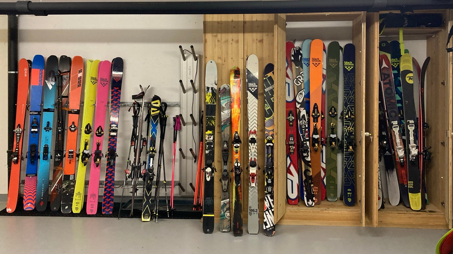 Garage with ski storage rack holding various skis and ski poles.